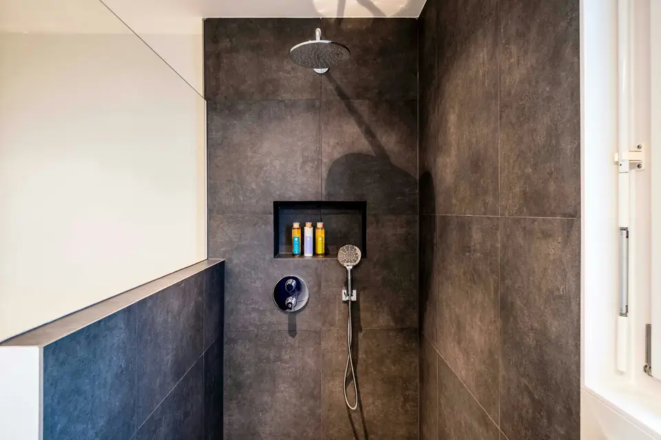 A walk-in shower with dark stone-look wall tiles