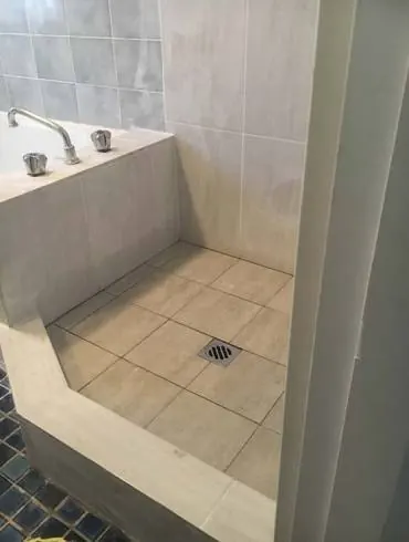 A newly tiled shower recess next to a bath