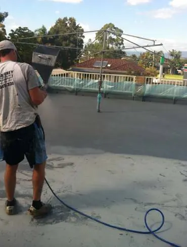 A Gaffneys tradesman spraying a waterproof coating on a flat roof deck