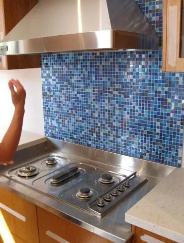 A blue mosaic splashback behind a cooktop