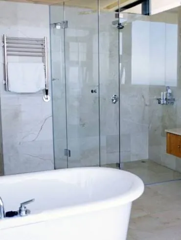 A walk-in shower with a frameless glass screen beside a freestanding bath