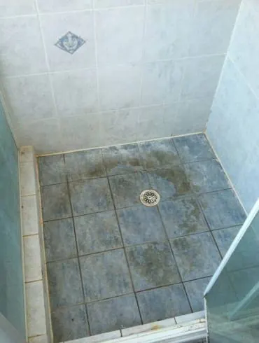 A shower floor with stained, failing grout