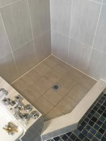 A tiled shower with a mosaic step-down hob