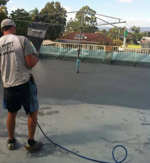 A Gaffneys tradesman hosing down a balcony surface during waterproofing work